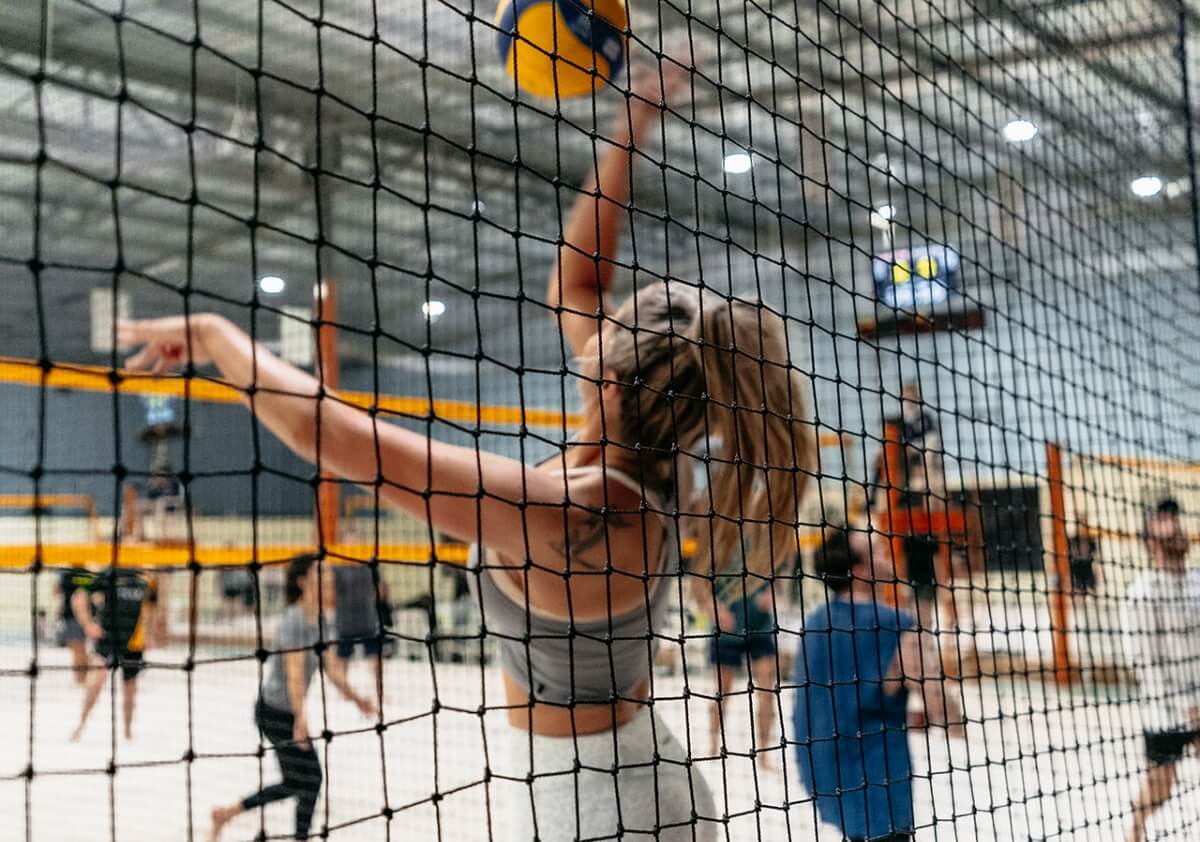 Player mid-spike seen through the volleyball net