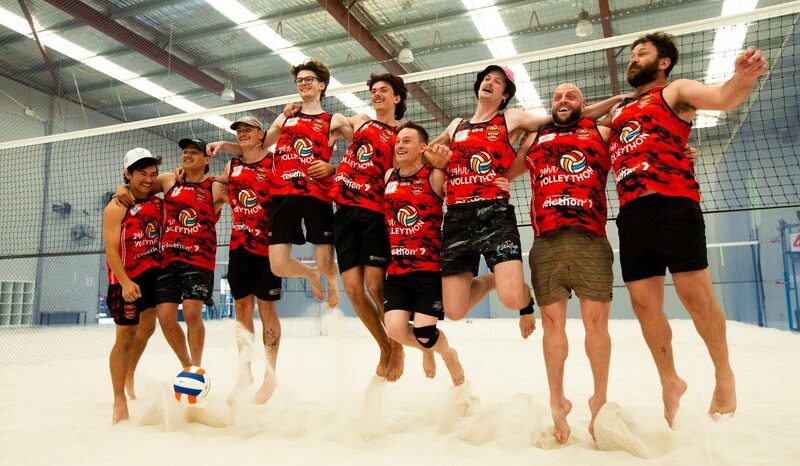 A team jumping for joy on the sand after a game