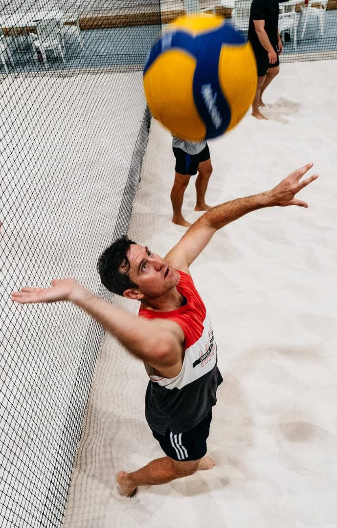 Player reaching up to spike a ball at the net