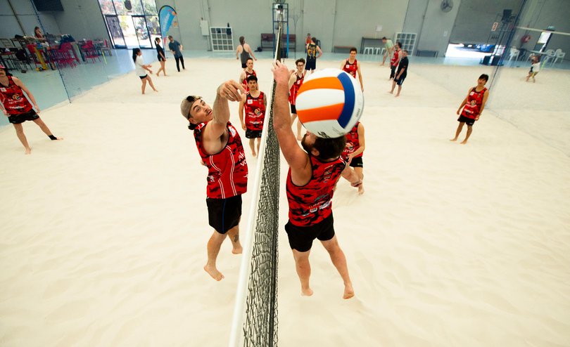 Players contesting the ball at the net on the sand courts